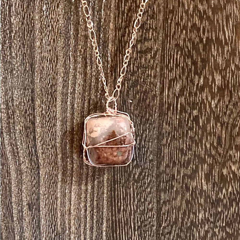 Wire-wrapped Rhodonite tumbled, smooth stone pendant on rose gold necklace.